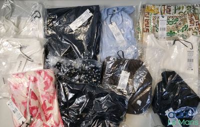 de nombreux vêtements de toutes sortes, rangés dans des sacs en plastique posés sur une table