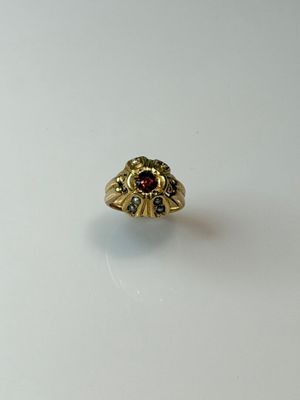 a close up of a gold ring with a red stone in the center