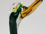 a green glass duck with a yellow beak on a white background