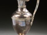 an antique silver plated pitcher with a handle on a stand