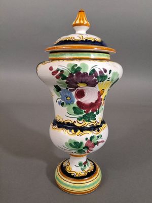 un vase muni d'un couvercle sur lequel sont peintes des fleurs
