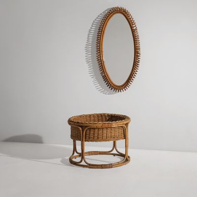 un miroir ovale accroché au mur au-dessus d'un panier en osier