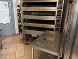 fours et tables en acier inoxydable dans une cuisine professionnelle dotée d'un carrelage au sol