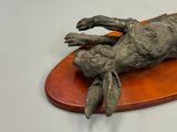a sculpture of a rabbit laying on top of a wooden board