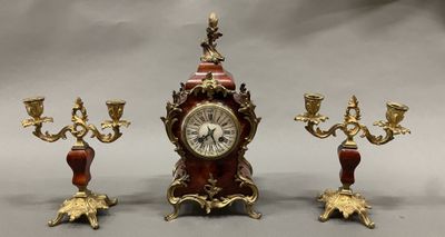 une horloge et trois bougeoirs placés les uns à côté des autres