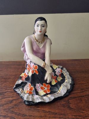 figurine of a woman sitting on top of a wooden table