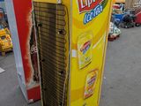 a large yellow soda machine sitting in a parking lot