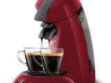 a red coffee maker with two cups of coffee in front of it