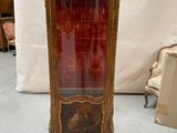 an antique display cabinet with a red glass door and gold trimming