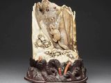 carved ivory figurine of a woman and a bird on a rock