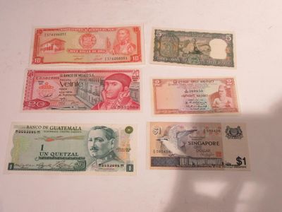cinq billets de banque différents posés sur une surface blanche