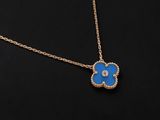a gold necklace with a blue flower pendant on a black background