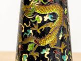 un vase noir orné d'un dragon, posé sur une table