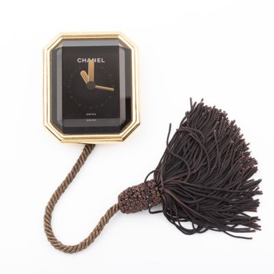 a black and gold clock with a tassel attached to it
