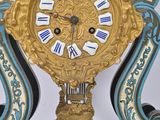 a gold and blue clock on a stand with a white background