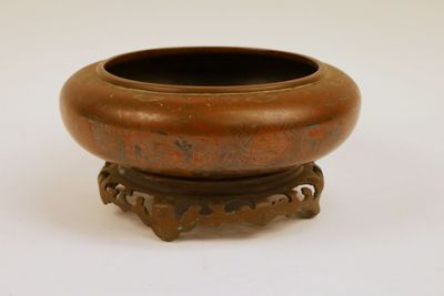 un petit bol en bronze posé sur un socle, sur une surface blanche