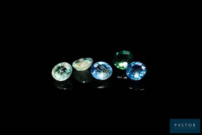 a close up of three different colored gems on a black surface