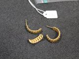 a close up of a pair of gold earrings on a table