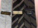 three ties with a label on them sitting on a pink surface