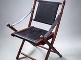 an old folding chair with a leather seat on a white background