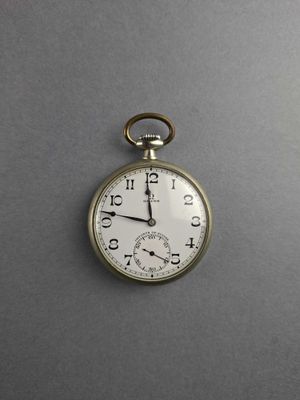 a silver pocket watch that is on a gray surface