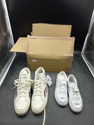 trois paires de baskets blanches sont posées à côté d'une boîte