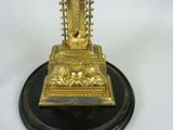 a gold clock on a black stand on a white background