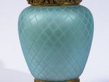 un vase bleu avec un socle doré sur fond blanc