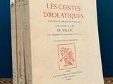 Plusieurs livres sont empilés sur une table devant un mur bleu.