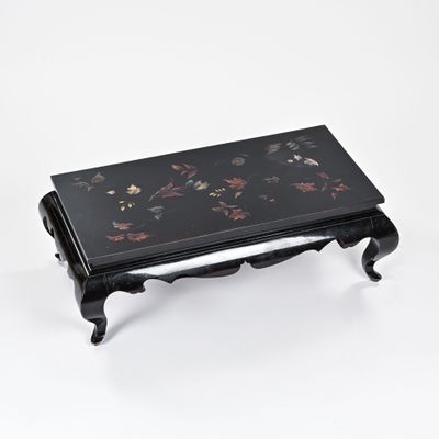 une photo d'une petite table noire sur laquelle sont disposées des fleurs