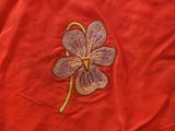 embroidered clover on a red t - shirt with a yellow thread