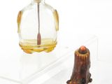 une petite bouteille en verre munie d'une poignée en bois, à côté d'une autre petite bouteille en verre munie d'une poignée en bois