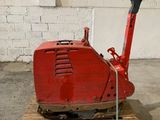 une machine rouge posée sur une palette devant un mur de briques