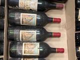 Plusieurs bouteilles de vin sont posées dans une boîte en carton sur un sol carrelé