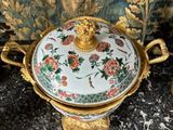 a gold and white bowl with a lid on a table