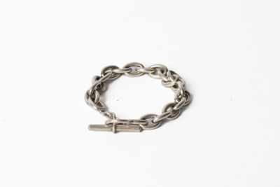 un gros plan d'un bracelet à maillons posé sur une surface blanche