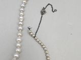 a close up of a white pearl necklace on a white surface