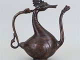 une image représentant une théière en bronze sur laquelle est représenté un oiseau au niveau de la poignée