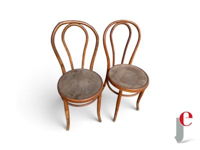 two wooden chairs with brown leather seats on a white surface