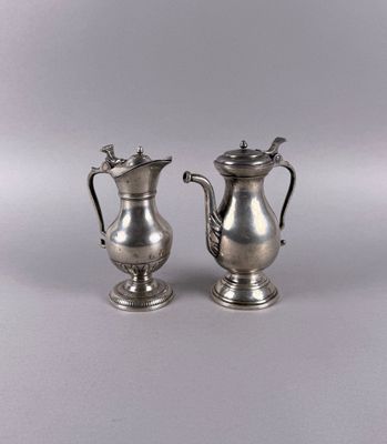 pair of silver plated coffee pots with handles on a grey background