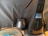 une table sur laquelle se trouvent un ventilateur, une télécommande et d'autres objets