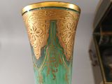 a green and gold vase sitting on a shelf next to a box