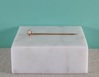 a white marble box with a gold pin on it