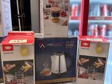 Trois boîtes de café sont empilées sur une table devant un réfrigérateur