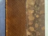 un vieux livre à la couverture marron posé sur une table blanche
