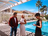 deux hommes et une femme debout près d'une piscine, un téléphone portable à la main