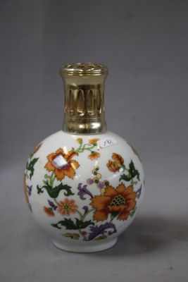 un petit vase blanc avec un couvercle doré posé sur une table