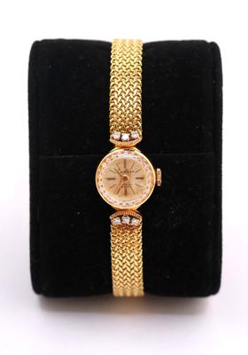 a close up of a gold watch on a black velvet case