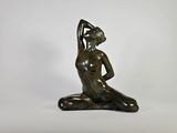 une statue en bronze représentant une femme assise à genoux