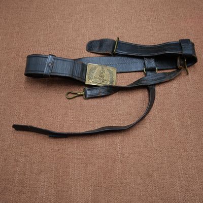 un gros plan d'une ceinture en cuir noir avec une boucle en laiton